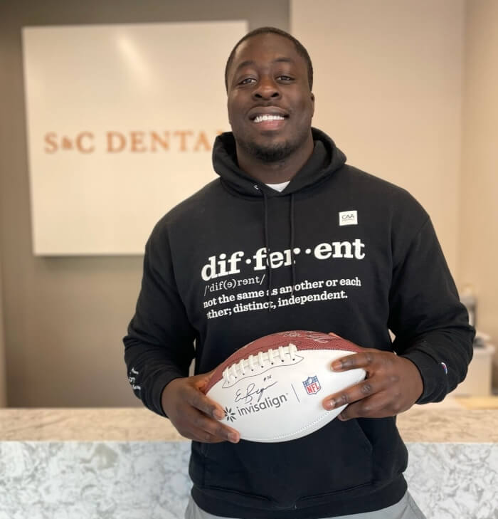 A man in a hoodie grips a football at S&C Dental in Scottsdale, AZ