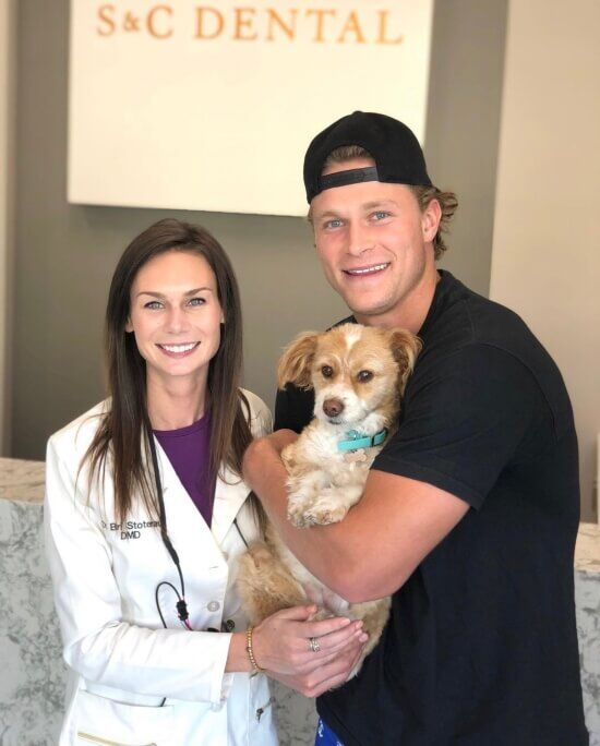 Dr. Bri posing with the patient and his dog at their dental clinic in Scottsdale, AZ