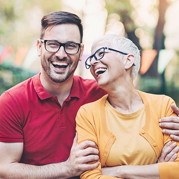 Man in red shirt hugging elderly woman in yellow