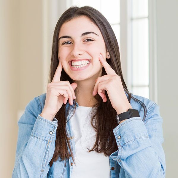 Young woman smiling pointing at cheeks after periodontal treatment in Scottsdale AZ