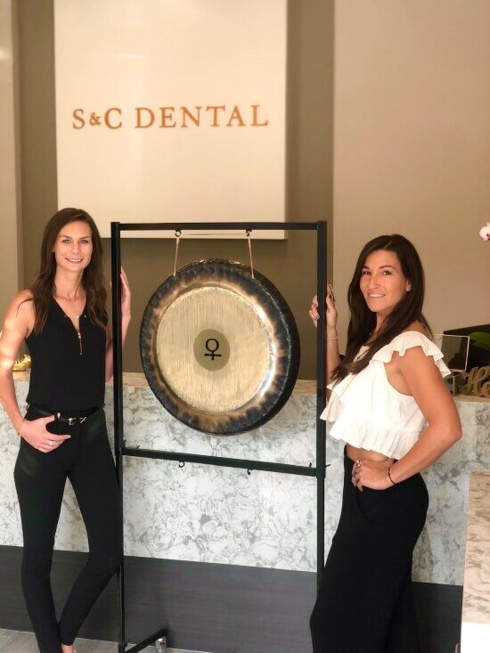 Two women stand in front of a sign reading S&C Dental in Scottsdale, AZ