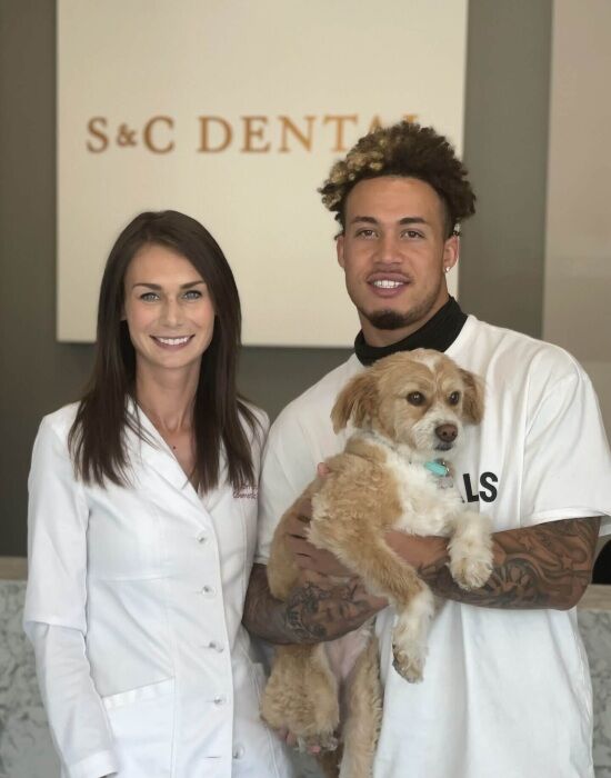 A dentist and a patient smiling while holding a dog in Scottsdale, AZ