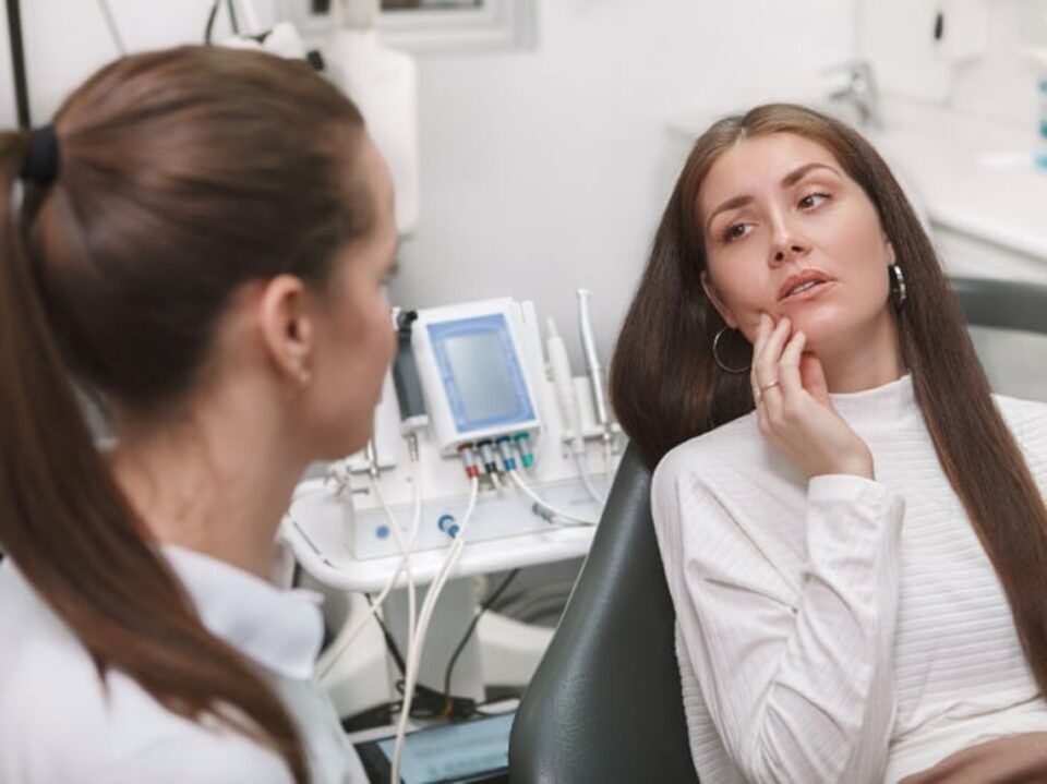 Woman experiencing tooth pain at the dentist