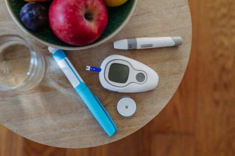 A bowl of fruit and a glucometer on a table