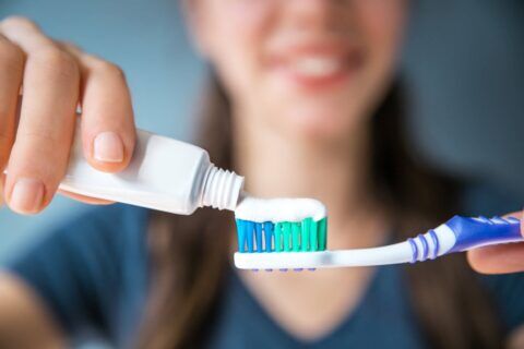 A person putting toothpaste on a toothbrush