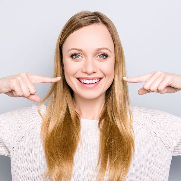 Women smiling pointing at face with both hands