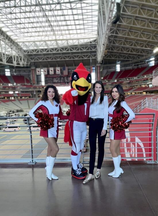 Cheerleaders and a mascot pose together at a Cardinals game in an indoor stadium in Scottsdale, AZ