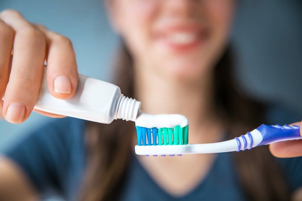 A person putting toothpaste on a toothbrush